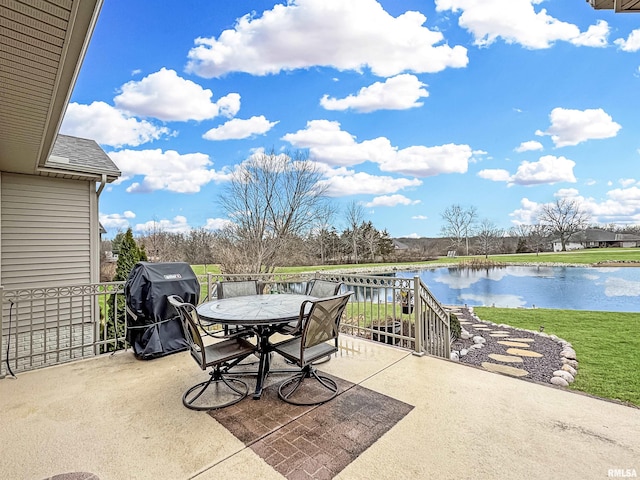 view of patio with outdoor dining space, a grill, and a water view