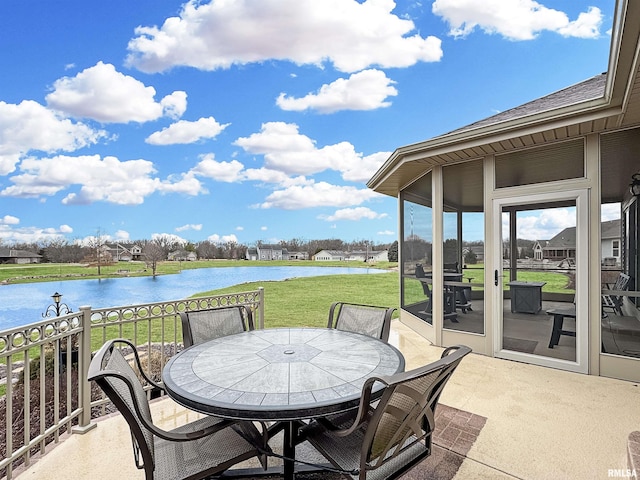 view of patio featuring outdoor dining space, a sunroom, and a water view