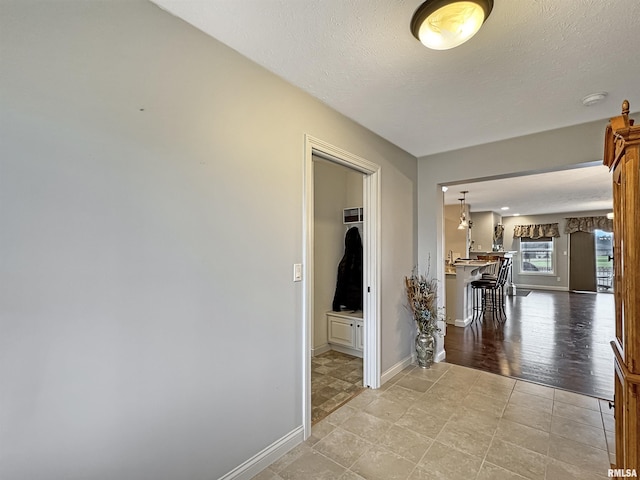 corridor with a textured ceiling and baseboards