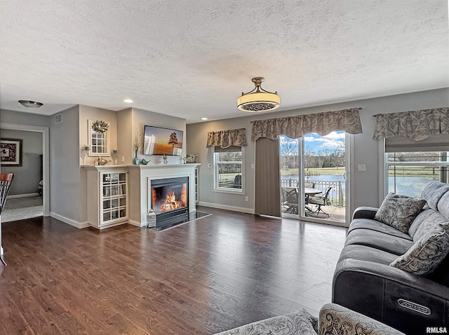 living area with a fireplace with flush hearth, wood finished floors, baseboards, and a textured ceiling