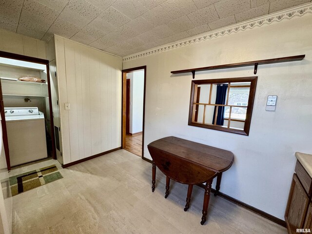 dining room featuring wooden walls, washer / dryer, and baseboards