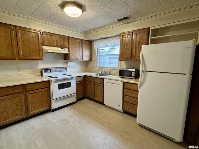 kitchen with under cabinet range hood, white appliances, a sink, visible vents, and brown cabinets