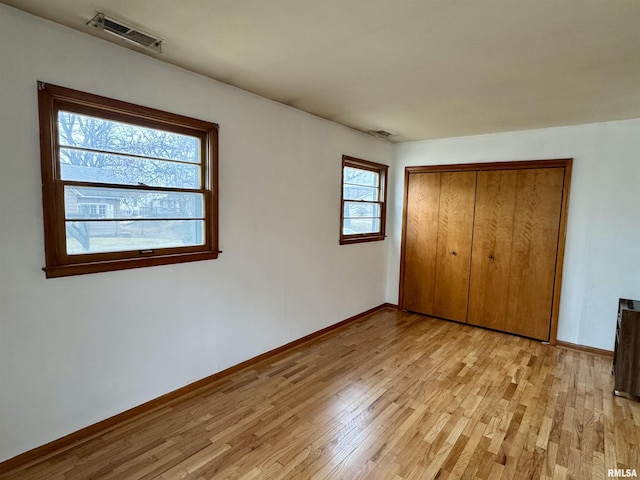 unfurnished bedroom with baseboards, a closet, visible vents, and light wood-style floors