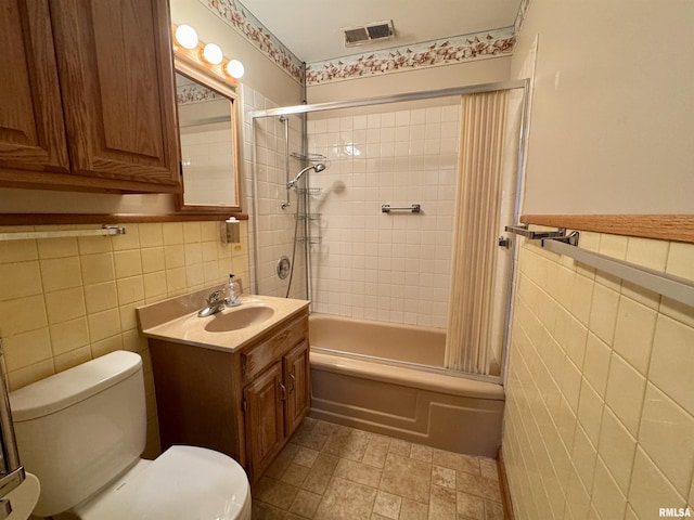 full bath with toilet, vanity, visible vents, tile walls, and shower / bathing tub combination