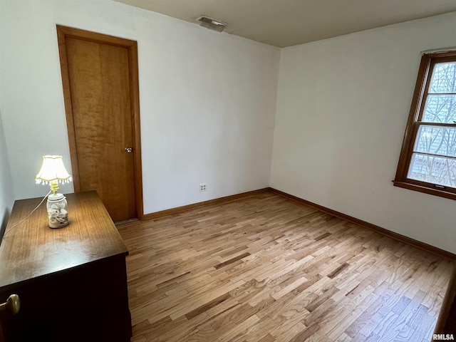 empty room featuring light wood-style flooring, visible vents, and baseboards