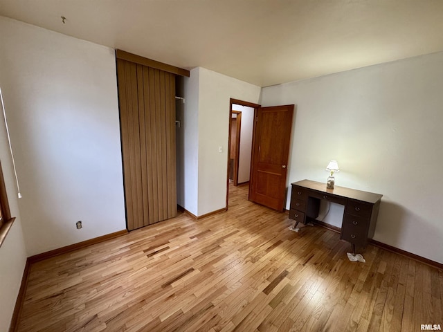 unfurnished bedroom with light wood finished floors, baseboards, and a closet