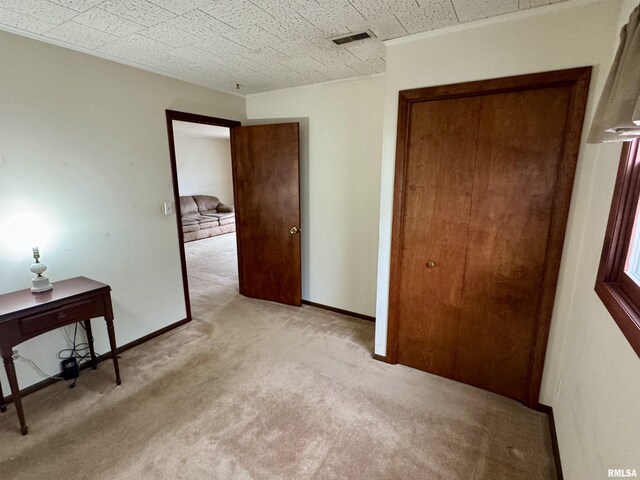 bedroom with light carpet, crown molding, a closet, and baseboards