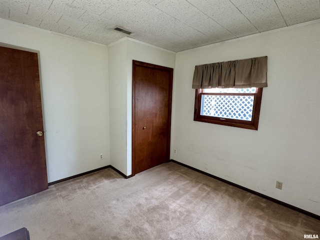 unfurnished bedroom featuring baseboards, carpet, visible vents, and a closet