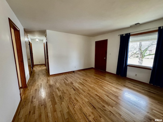 unfurnished room featuring light wood-style flooring, visible vents, and baseboards