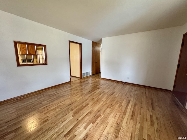 unfurnished room featuring visible vents, light wood-style flooring, and baseboards