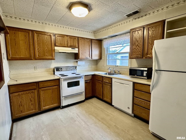 kitchen with brown cabinets, a sink, light wood-type flooring, white appliances, and under cabinet range hood