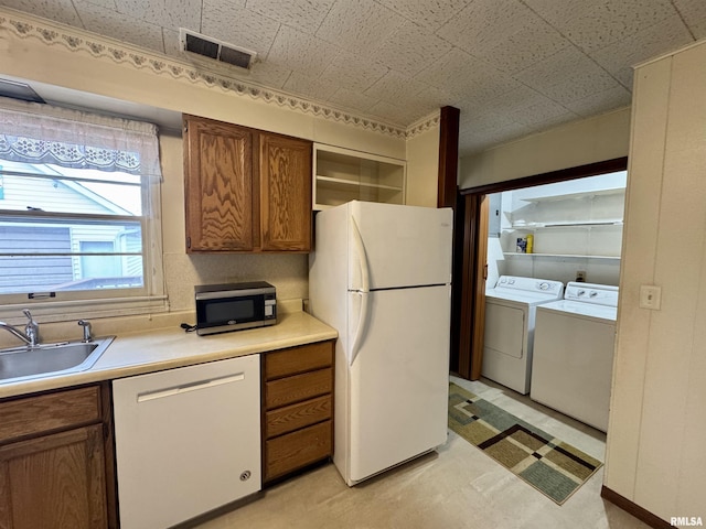 kitchen with white appliances, visible vents, independent washer and dryer, open shelves, and a sink