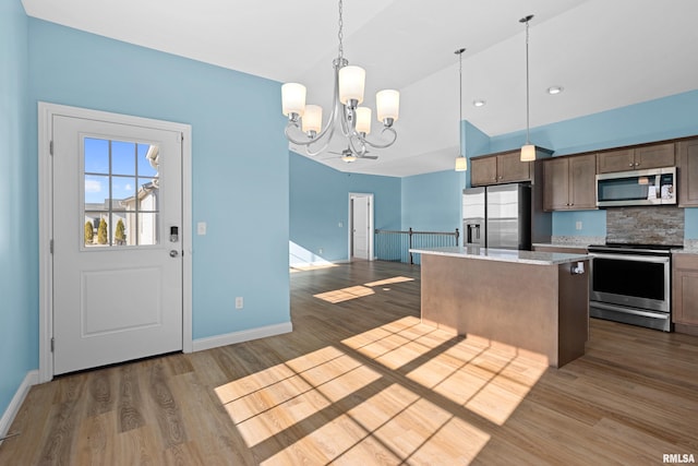 kitchen featuring stainless steel appliances, wood finished floors, a kitchen island, and a notable chandelier