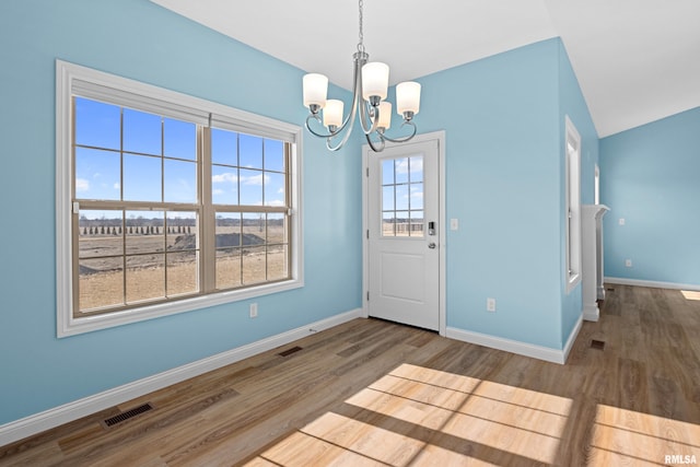 interior space with a notable chandelier, wood finished floors, visible vents, and baseboards