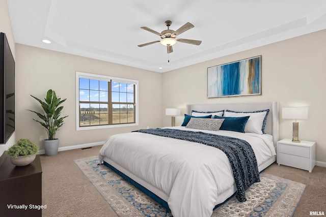 bedroom with carpet floors, visible vents, baseboards, and a raised ceiling