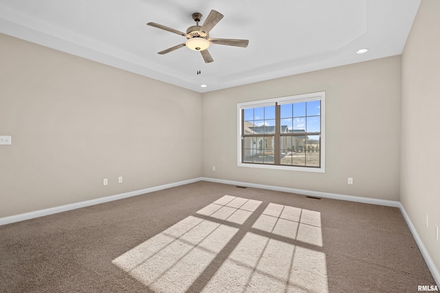 unfurnished room with a ceiling fan, a tray ceiling, carpet floors, and baseboards