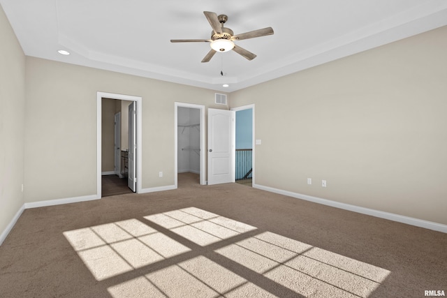 unfurnished bedroom featuring recessed lighting, visible vents, baseboards, a spacious closet, and a tray ceiling