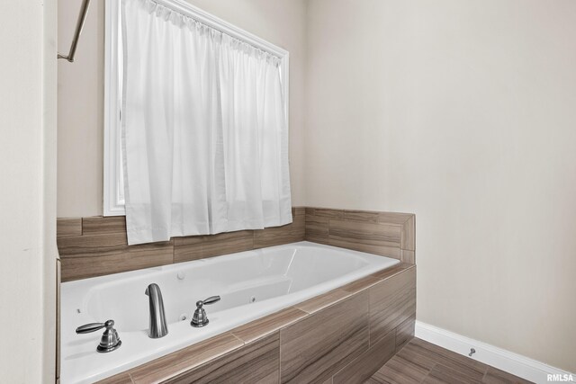 bathroom with a garden tub and baseboards