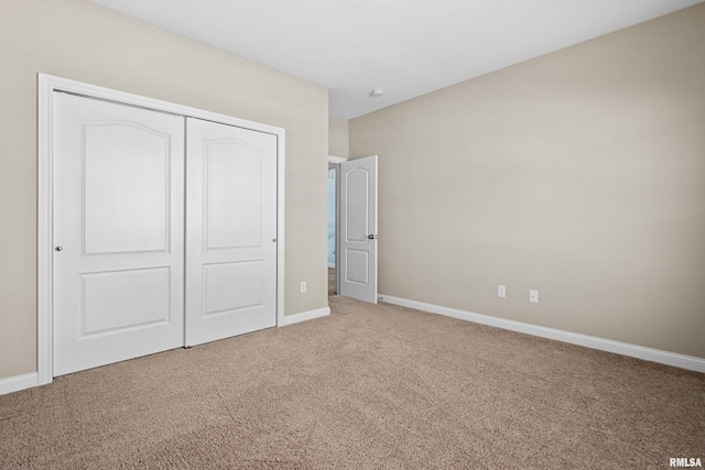 unfurnished bedroom with a closet, carpet flooring, and baseboards