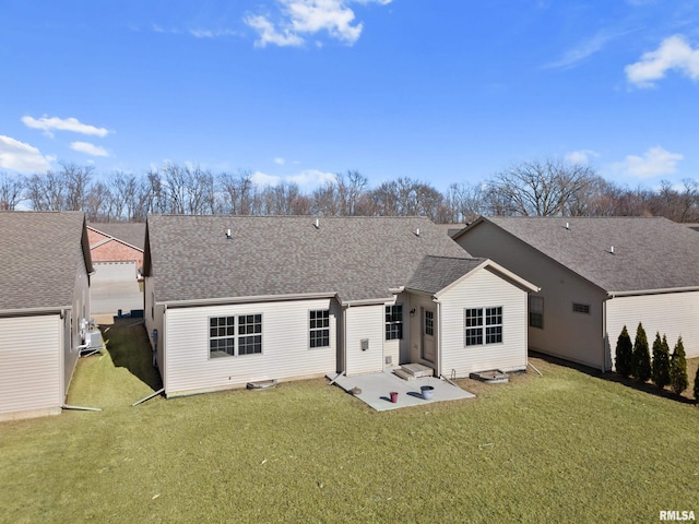 rear view of house featuring a shingled roof, a patio, and a yard