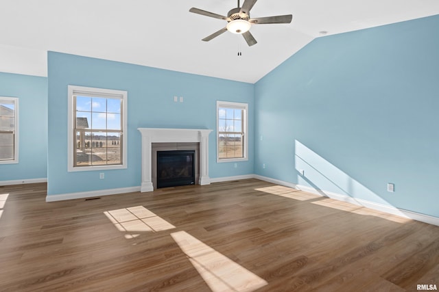 unfurnished living room featuring lofted ceiling, baseboards, wood finished floors, and a glass covered fireplace