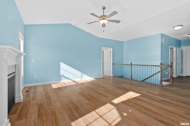 unfurnished living room with lofted ceiling, a fireplace, wood finished floors, and baseboards