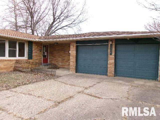 ranch-style home with concrete driveway, brick siding, and an attached garage