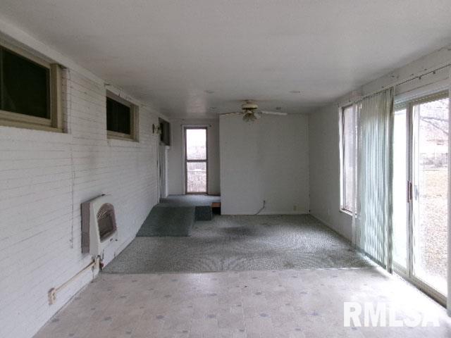 unfurnished living room featuring ceiling fan and heating unit