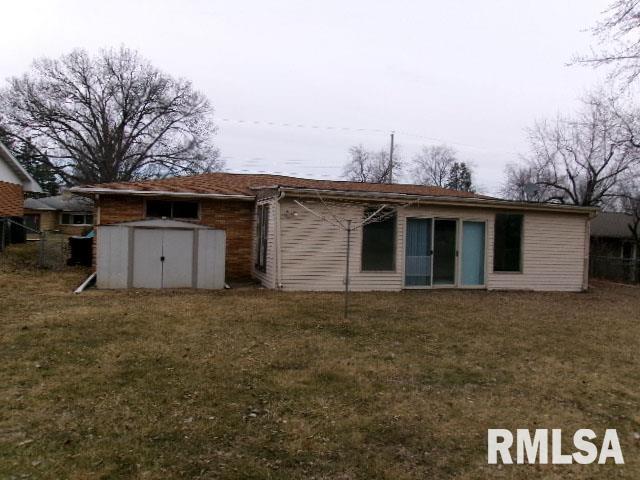 back of property with a storage shed, a lawn, and an outdoor structure