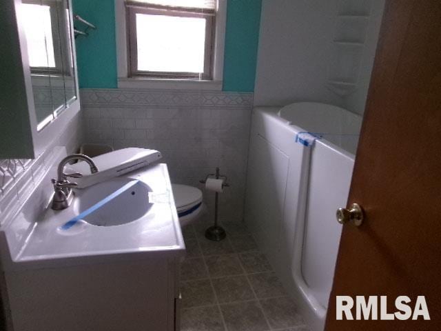 full bath featuring vanity, a wealth of natural light, tile patterned flooring, and toilet