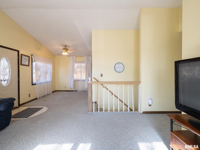 unfurnished living room with vaulted ceiling, carpet floors, a ceiling fan, and baseboards