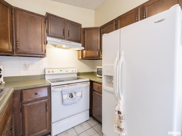 kitchen featuring white appliances, light countertops, under cabinet range hood, and backsplash