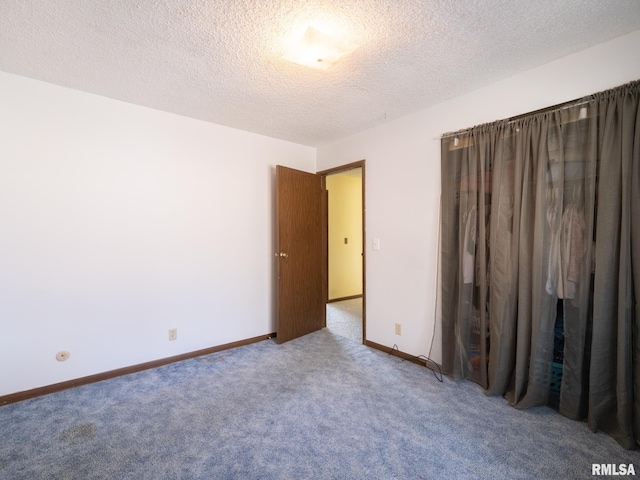 unfurnished bedroom with carpet, a textured ceiling, and baseboards