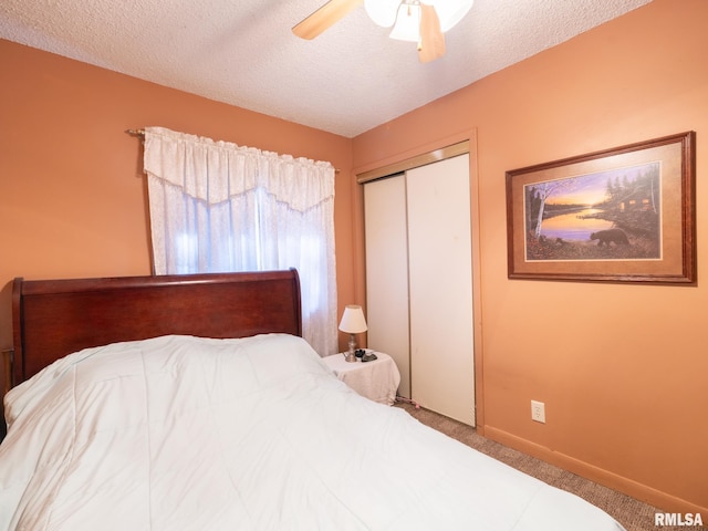 carpeted bedroom with ceiling fan, a textured ceiling, baseboards, and a closet