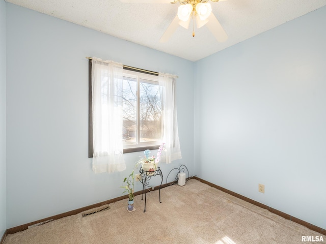 carpeted empty room featuring a ceiling fan, visible vents, and baseboards