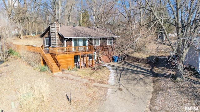 chalet / cabin featuring stairs, driveway, a deck, and a chimney