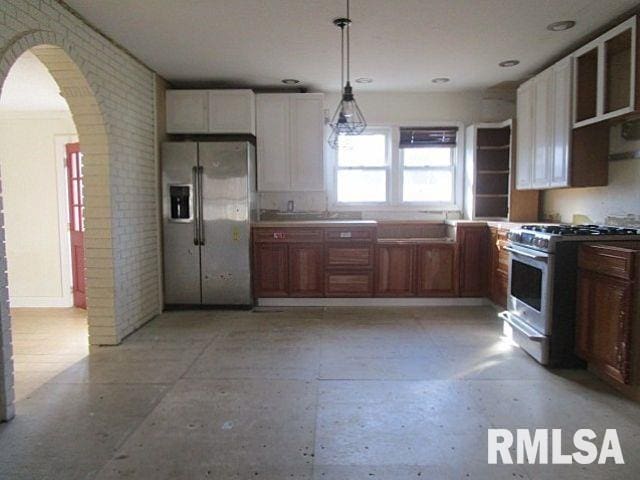 kitchen featuring appliances with stainless steel finishes, arched walkways, white cabinets, and decorative light fixtures