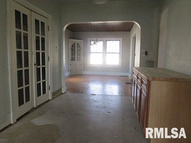 unfurnished dining area featuring arched walkways, french doors, and baseboards