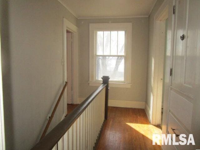 hallway with light wood-type flooring, an upstairs landing, and baseboards