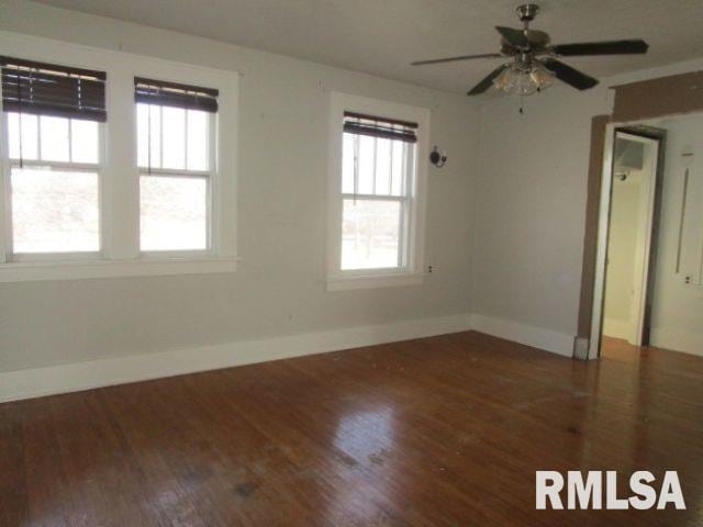 spare room with baseboards, a wealth of natural light, and wood finished floors