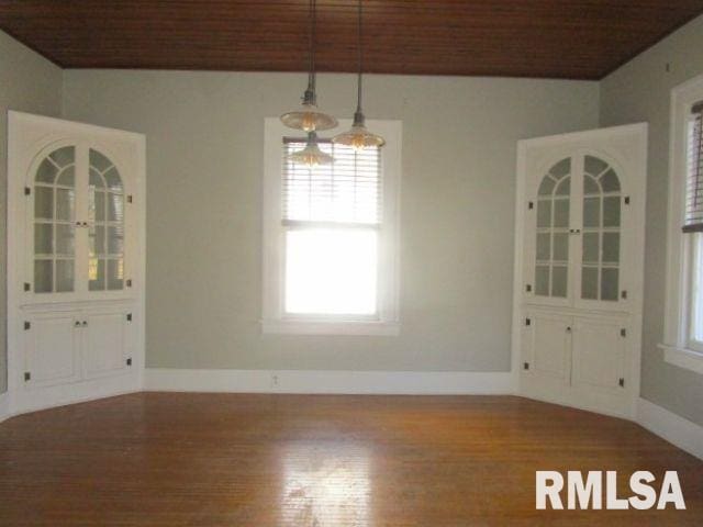 unfurnished dining area featuring baseboards and wood finished floors