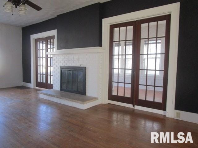 unfurnished living room featuring a ceiling fan, a fireplace, and wood finished floors