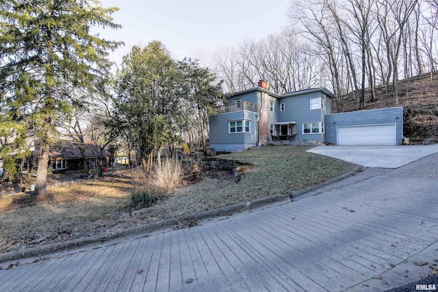 view of front of property featuring concrete driveway, a chimney, and an attached garage