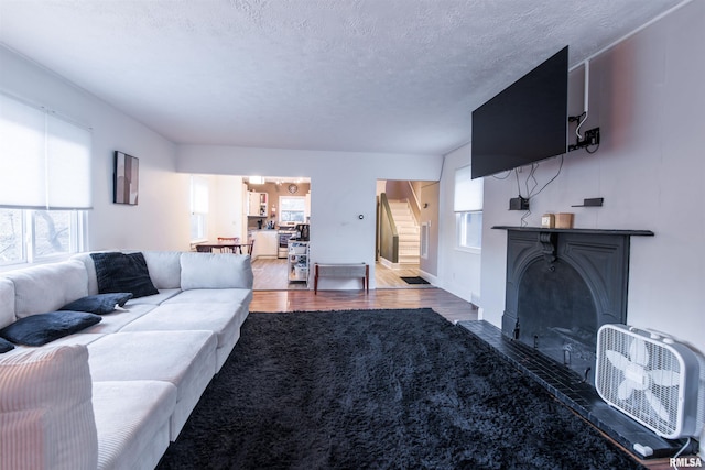 living area featuring a textured ceiling, stairway, wood finished floors, and baseboards