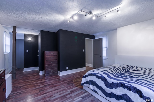 bedroom with a textured ceiling, baseboards, and wood finished floors