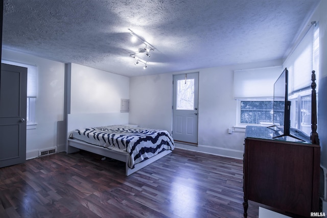 bedroom featuring a textured ceiling, wood finished floors, visible vents, and baseboards