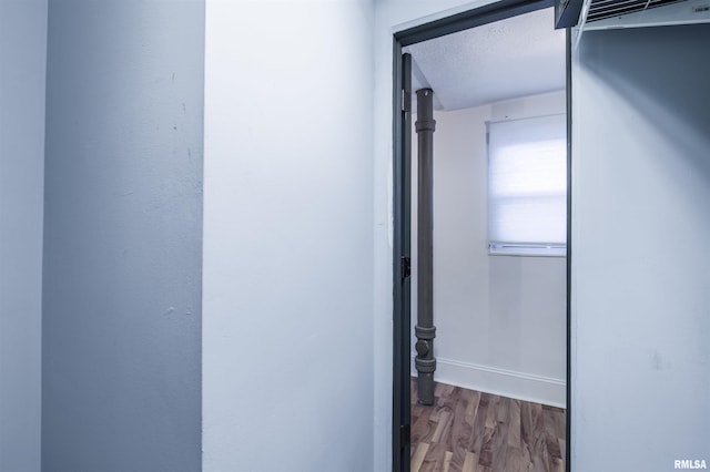 hall with a textured ceiling, baseboards, and wood finished floors