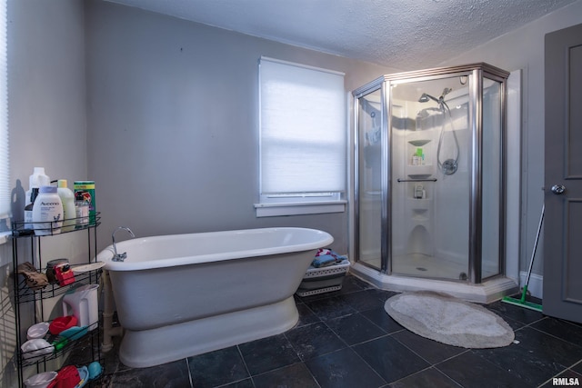 full bathroom featuring a freestanding bath, a shower stall, a textured ceiling, and tile patterned floors