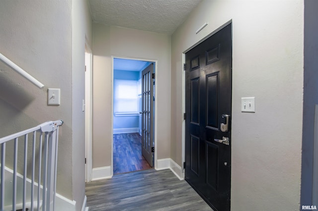 entryway featuring stairway, a textured ceiling, baseboards, and wood finished floors