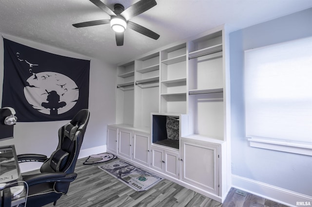 home office with a ceiling fan, baseboards, a textured ceiling, and wood finished floors